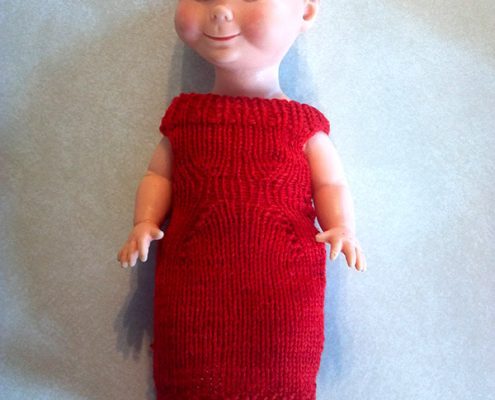 Baby doll in a red handknit dress.